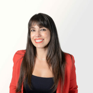 Elisa Costante stands in front of white wall and smiles into the camera.